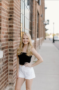 A woman smiles with her hand on the hip. 